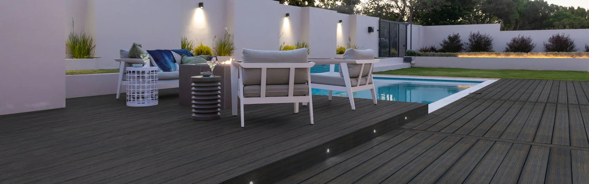 Terrasse en bois composite PVC foncé avec mobilier extérieur près d'une piscine moderne