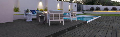 Terrasse en bois composite PVC foncé avec mobilier extérieur près d'une piscine moderne