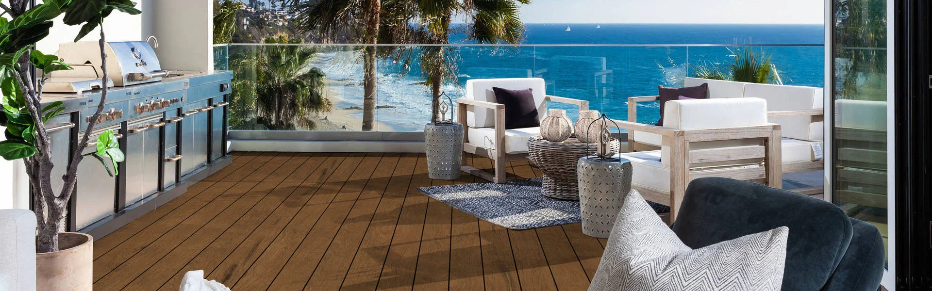 Terrasse en PVC imitation bois naturel Ipe avec salon extérieur face à la mer, cuisine et palmiers