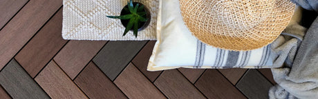 Lames de terrasse composite marron et gris en chevrons, coussin, chapeau et plante décorative
