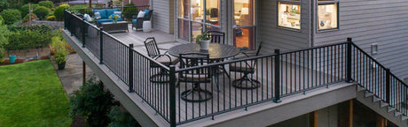 Terrasse en composite gris avec garde-corps, salon de jardin et vue sur jardin verdoyant
