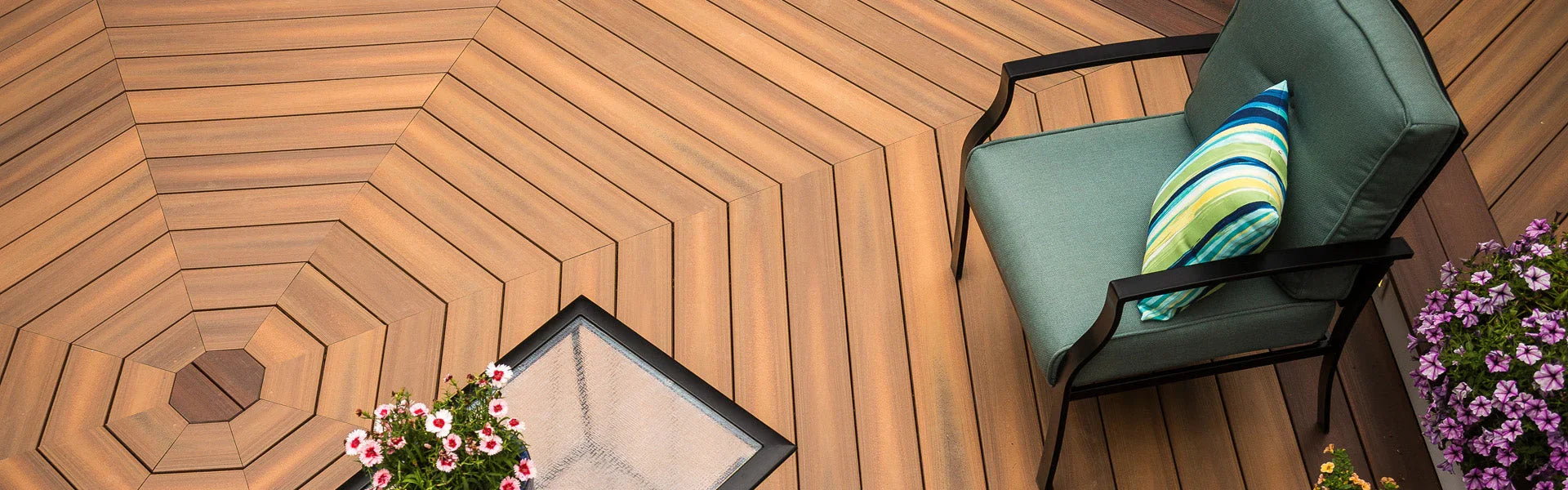 Terrasse en bois composite, chaise extérieure verte et fleurs roses, aménagement moderne.