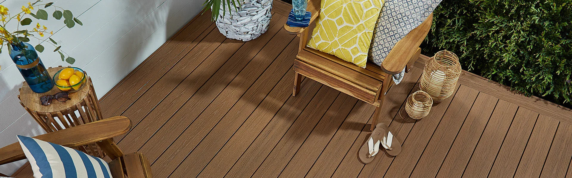 Terrasse en bois composite aménagée avec fauteuil en bois et coussins, décor extérieur accueillant.