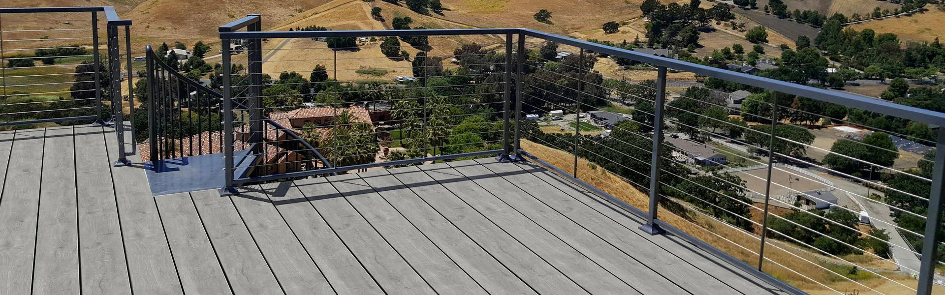 Terrasse avec lames de bois gris cendré et rambarde métallique, vue sur campagne