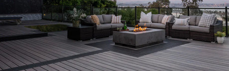 Terrasse en bois composite gris avec salon de jardin et foyer extérieur moderne, vue panoramique.
