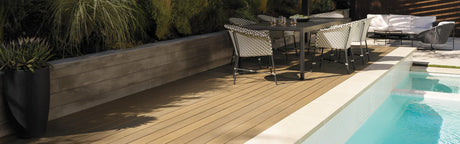 Terrasse en composite aspect bois près d'une piscine, mobilier extérieur moderne, ambiance jardin