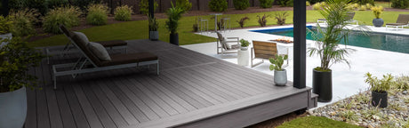 Terrasse en bois composite gris avec chaises longues, plantes et piscine extérieure