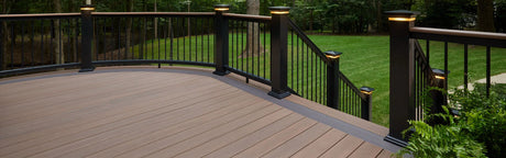 Terrasse en composite bois PVC couleur noyer foncé avec garde-corps noir, vue sur jardin