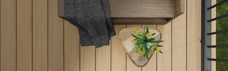 Planches de terrasse en bois clair avec banc, plaid gris et plante décorative