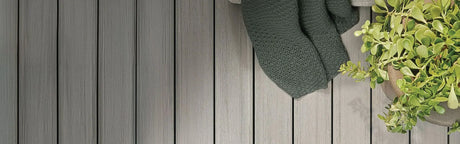 Planches de terrasse en bois gris, plaid et plante verte en pot, ambiance extérieure moderne